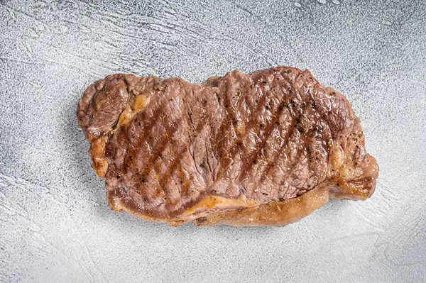 Grilled New York striploin beef meat steak. White background. Top view.