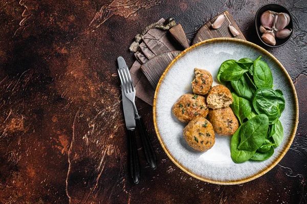 Fish Cakes or Fish balls with tuna and spinach in a plate. Dark background. Top view. Copy space.