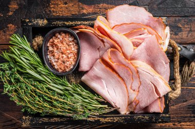 İtalyan Prosciutto Cotto Jambonu ahşap tepside kekik ve biberiyeyle dilimler. Ahşap arka plan. Üst görünüm.