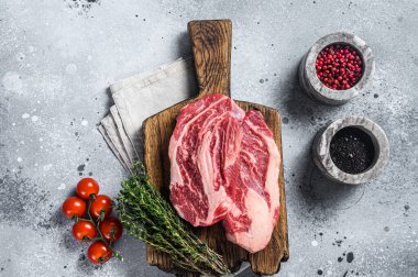 Tahta bir tahtanın üzerinde kekik ile çiğ Chuck Roll biftekleri. Gri arka plan. Üst görünüm.