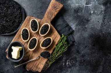 Tahta üzerinde Sturgeon Black havyarı olan turtalar. Siyah arka plan. Üst Manzara. Boşluğu kopyala.