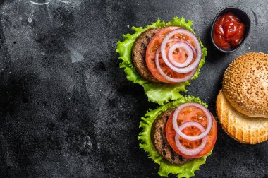 Vegan burger with Plant based meatless cutlets, patties, tomato and onion. Black background. Top view. Copy space.