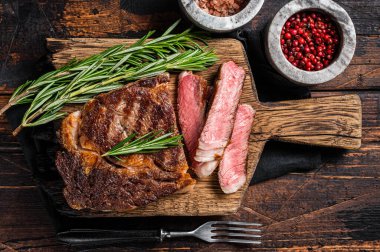 Dilimlenmiş ve ızgara pirzola bifteği, ahşap bir tahtanın üzerinde kaburga eti. Ahşap arka plan. en üstteki görünüm.