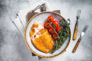 Çıtır ekmekli tilapia dolguları bir tabakta sebzelerle birlikte. Beyaz arka plan. Üst görünüm.