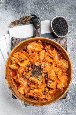 Kimchi cabbage in a wooden plate with chopsticks for eating , Korean cuisine. White background. Top view.