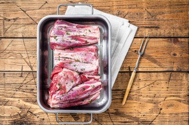 Marinated lamb shanks with herbs, spices and thyme. Mutton meat ready for cooking. Wooden background. Top view.