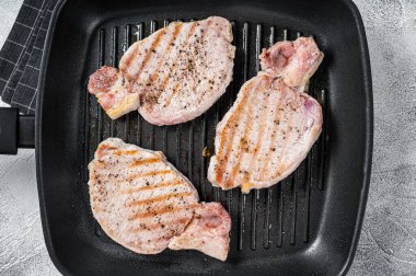 Fried on a grill skillet pork chop steaks. White background. Top view.