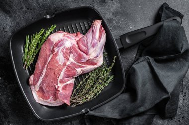 Ready for cooking lamb whole shoulder, raw leg meat on a grill pan with spices. Black background. Top view.