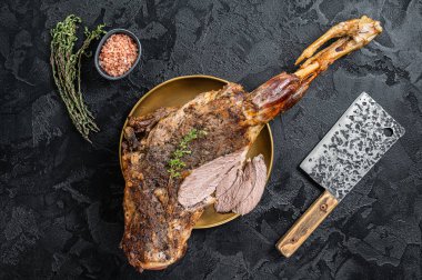 Christmas dish - Roast lamb leg meat with spices and thyme on a plate. Black background. Top view.