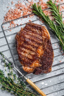 Barbekü ızgara kaburga bifteği, ızgarada otlu biftek eti. Gri arka plan. en üstteki görünüm.