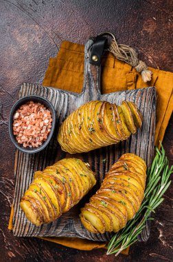 Roasted Hasselback Potato with Fresh thyme and rosemary. Dark background. Top view.