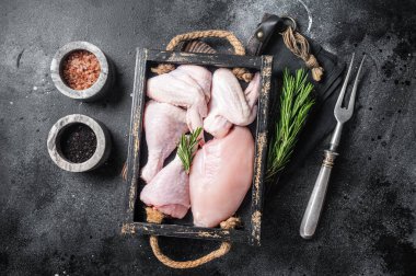Taze çiğ tavuk eti ve tavuk parçaları - but, göğüs filetosu, kanat, but. Siyah arka plan. Üst görünüm.