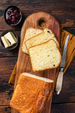 Kahvaltı masasında tereyağı ve reçelli Brioche ekmeği. Ahşap arka plan. Üst görünüm.