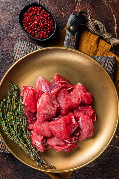 Raw diced lamb mutton meat with thyme. Dark background. Top view.