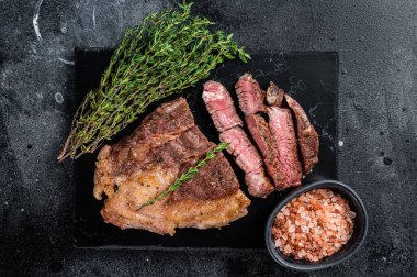 Kızarmış bbq Chuck Roll bifteği ve otlar. Siyah arka plan. Üst görünüm.