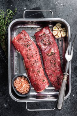 Kuzu fileto fileto pişirmek otlu et ve zeytin yağı, mutfak tepsisinde marine edilmiş koyun eti. Siyah arka plan. Üst görünüm.