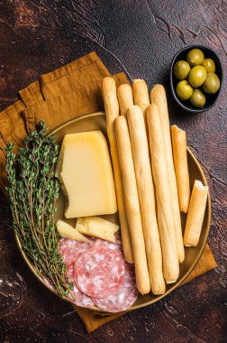 Antipasti aperatifli Grissini ekmek çubukları, salam, zeytin ve parmesan peyniri. Koyu fırın. Üst görünüm.