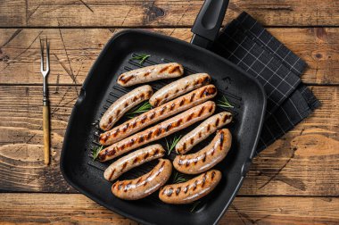 Grilled homemade sausages with Beef, pork, lamb and chicken mince meat in a grill skillet. Wooden background. Top view.