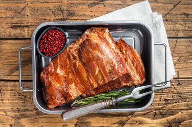 American Smoked Pork spare Ribs in steel tray with herbs. Wooden background. Top view.