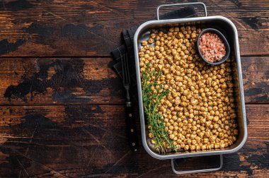 Mutfak tepsisinde vejetaryen aperatifi kızarmış baharatlı nohut. Ahşap arka plan. Üst Manzara. Boşluğu kopyala.