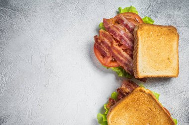 BLT toasted sandwich with bacon, tomato and lettuce. Gray background. Top view. Copy space.