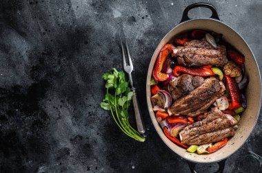 Braised slow cooked lamb shank in red wine sauce with vegetables in cooking pot. Black background. Top view. Copy space.