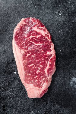 Raw Striploin steak, beef butchery cut. Black background. Top view.