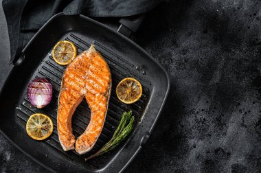 Izgarada otlarla ızgara edilmiş somon balığı bifteği. Siyah arka plan. Üst Manzara. Boşluğu kopyala.