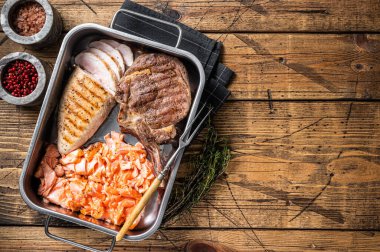 Set of roasted meat steaks salmon, beef veal and chicken in a kitchen tray with herbs. Wooden background. Top view. Copy space.