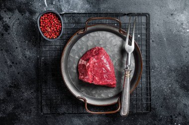 Piece of raw rump steak prepared for cooking. Black background. Top view.