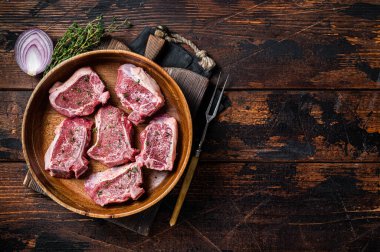 Çiğ kuzu fileto kaburga pirzola, ahşap tabakta biftek ve şifalı otlar. Ahşap arka plan. Üst Manzara. Boşluğu kopyala.