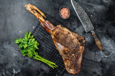 BBQ Roasted lamb mutton leg with herbs and spices on a grill. Black background. Top view.