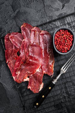 Dried sliced basturma, cured beef meat ready for eat. Black background. Top view.