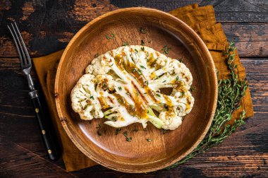 Grilled Cauliflower steaks with a cilantro lime chimichurri sauce, Plant based meat substitute concept. Wooden background. Top view.