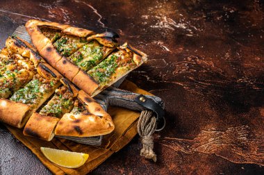 Traditional Turkish baked pide, Middle Eastern snack. Turkish pizza. Dark background. Top view. Copy space.