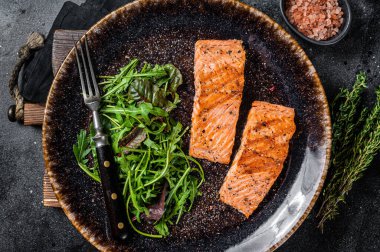 Barbekü vejetaryen yemeği - salatalı ızgara somon fileto bifteği. Siyah arka plan. Üst görünüm.