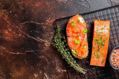 Open sandwich toast with cold smoked salmon fillet, spices. Dark background. Top view. Copy space.