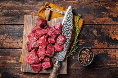 Sliced Raw venison dear meat for a stew, game meat on butcher cutting board. Wooden background. Top view.