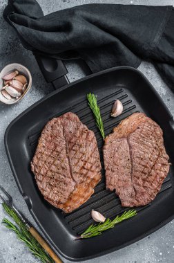 Izgara tavada kızartılmış sığır eti mermer biftekler. Gri arka plan. Üst görünüm.
