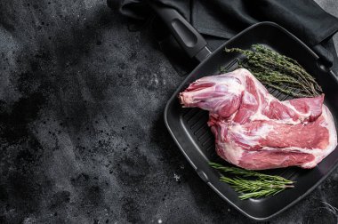 Ready for cooking lamb whole shoulder, raw leg meat on a grill pan with spices. Black background. Top view. Copy space.