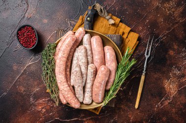 Assorted raw homemade sausages with Beef, pork, lamb and chicken meat on a plate. Dark background. Top view.