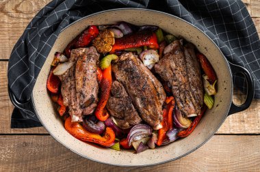 Roasted slow cooked lamb shanks with vegetables and herbs. Wooden background. Top view.