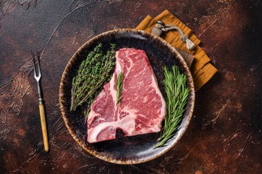 Kurumuş çiğ biftek bifteği, taze biftek ve baharatlı rustik tabak. Karanlık arka plan. Üst görünüm.