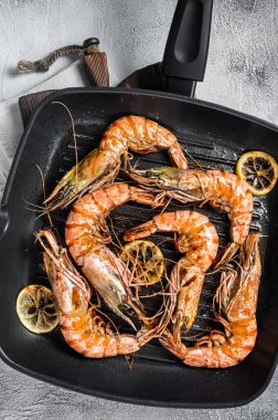 Izgara tavada kızartılmış dev siyah kaplan karidesli limon ve otlu karides. Gri arka plan. Üst görünüm.