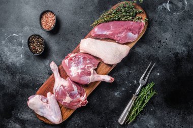 Çiğ ördek eti pişmeye hazır, göğüs filetosu, bacaklar, kanatlar. Siyah arka plan. Üst görünüm.