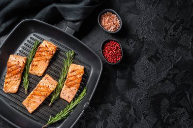 Roasted salmon fillets steaks on grill skillet. Black background. Top view. Copy space.