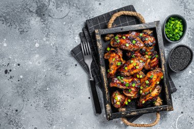 BBQ Chicken wings in Teriyaki sauce with black sesame in a tray. Gray background. Top view. Copy space.