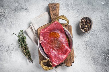 Kanat bifteği, tavada çiğ et, otlar ve zeytinyağı. Beyaz arka plan. Üst görünüm.