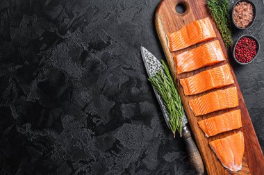 Sliced salmon fillet, raw fish meat with thyme and rosemary. Wooden background. Top view. Copy space.