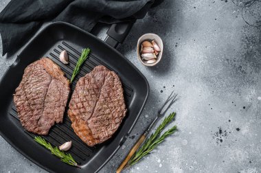 Roasted on grill skillet beef marbled meat steaks. Gray background. Top view. Copy space.